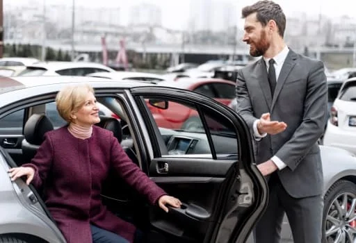 Senhora elegante sendo assistida por motorista ao sair de carro de luxo para evento em Belo Horizonte